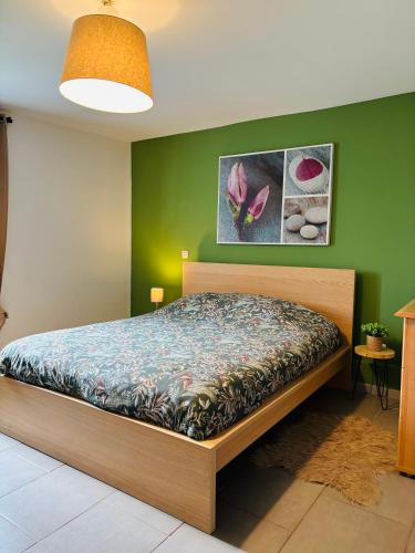 a bedroom with a bed in a green wall at Le gîte du faubourg in Sautour