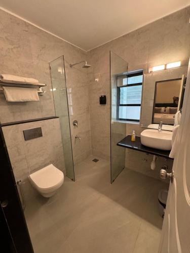 a bathroom with a toilet and a sink and a shower at Ocean White Sands Resort & Spa in Varca