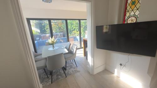 a dining room with a white table with chairs and a television at Superb luxury stay Croydon London in Thornton Heath