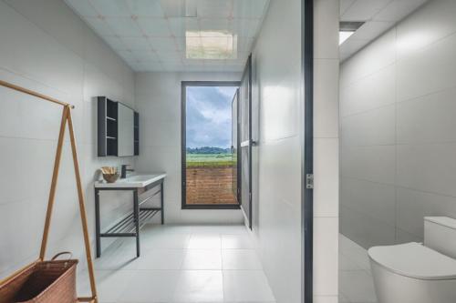 a bathroom with a toilet and a sink and a window at Xinwo Homestay in Pan-na-meng-hun