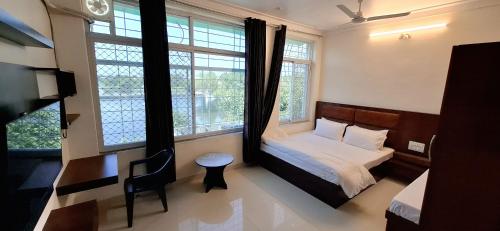 Un dormitorio con una cama y un escritorio y dos ventanas. en Antariksh, en Udaipur