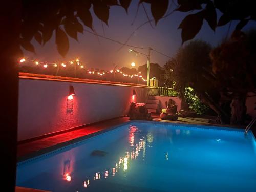 Una mujer sentada junto a una piscina por la noche en B&B Casa da Ponte Selmes Vidigueira, en Selmes