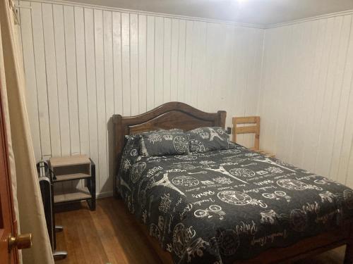 a bedroom with a bed with a black and white comforter at Precioso alojamiento centro Coyhaique in Coihaique
