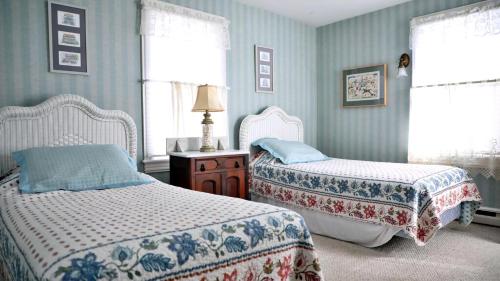 une chambre avec deux lits et une table avec une lampe dans l'établissement The Windsor Cottage, à Cape May