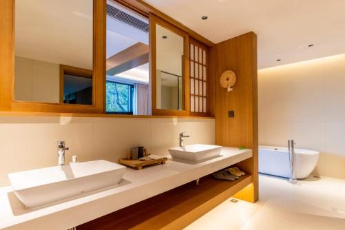a bathroom with two sinks and a tub at 重庆金佛山古核隐庐Resort Hotel in Nanchuan