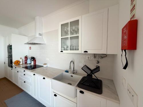 eine Küche mit weißen Schränken und einer Spüle in der Unterkunft Casa das Laranjeiras in Torrão