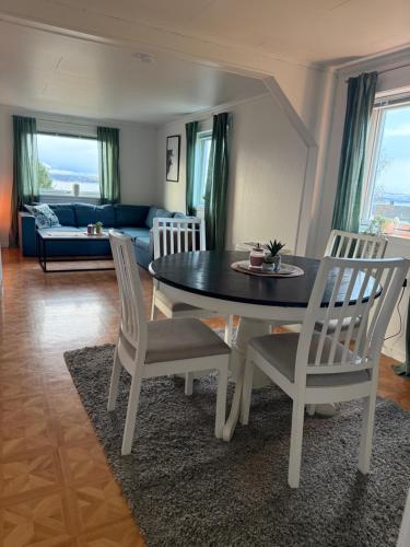 Una mesa de comedor y sillas en una sala de estar. en Sigridtunet - 4 bedroom Arctic experiences by the sea, with great opportunities to see the Northern lights dancing just for you!, en Tromsø