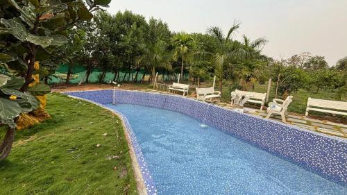 a swimming pool in a yard with benches next to it at SR Farm Stay in Turkapally