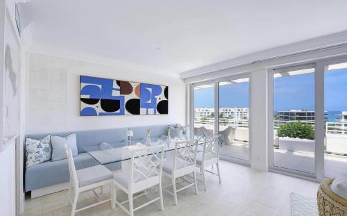 a dining room with a blue couch and a table at Luxury Three Bedroom Oceanfront Penthouse with Ter in Palm Beach