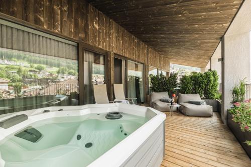 a large bath tub in a room with a patio at Aquila Dolomites Residence in Ortisei