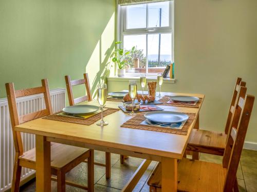 a dining room table with chairs and a wooden table with wine glasses at Clayhills Cottage - Uk5833 in Rattray