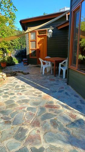 a patio with a table and chairs in front of a house at Las Palmas Lodge in Olmué