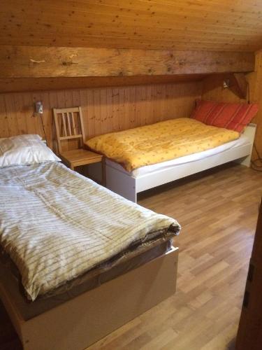 two beds in a room with wooden walls at Appartement La Croix in Villarvolard