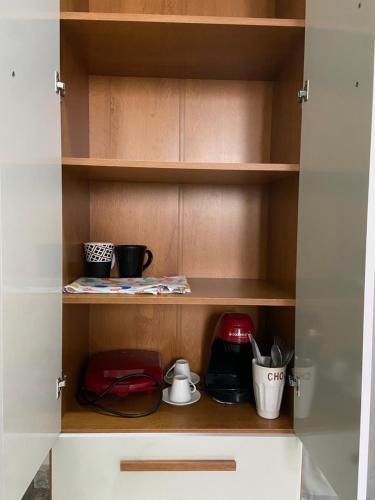 a cupboard with various kitchen items in it at Suíte Pontal in Arraial do Cabo