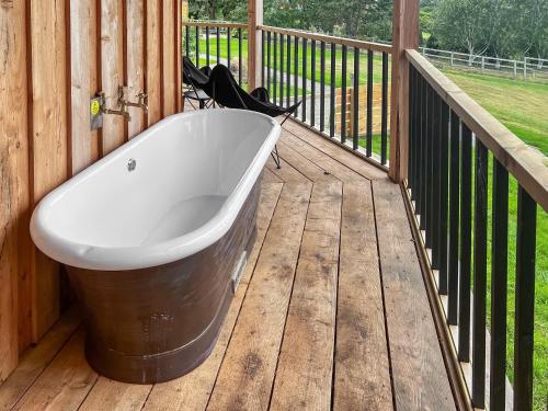 a bath tub sitting on a wooden deck at The Rabbit Hole - Uk50123 in Bodelwyddan