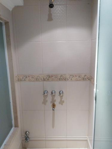 a shower with white tile and silver faucet at Hotel A&B Internacional in Buenos Aires