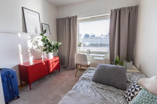 a bedroom with a bed and a red dresser and a window at Big river view city apartment in Rovaniemi