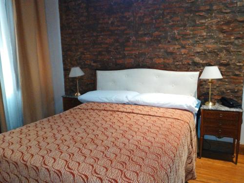 a bedroom with a bed and a brick wall at Hotel A&B Internacional in Buenos Aires
