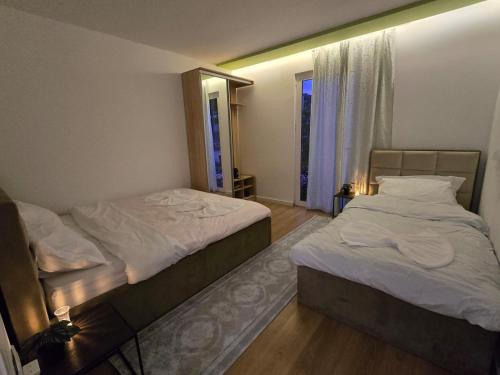 two twin beds in a room with a mirror at Neva's Hostel in Librazhd