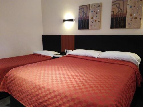 two beds in a hotel room with red sheets at Hotel A&B Internacional in Buenos Aires