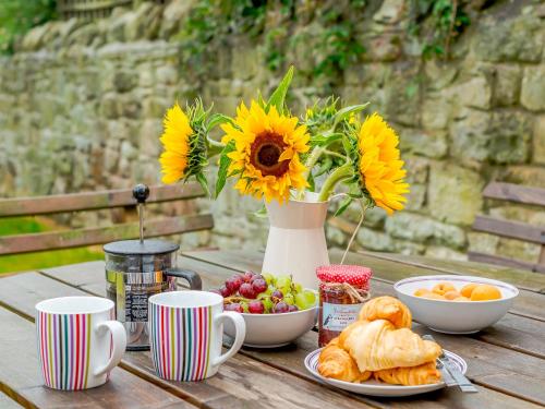 a table with a vase of sunflowers and a plate of food at Seaglass House in Beadnell