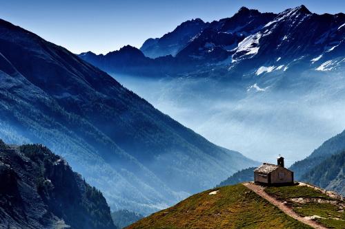 a small house on a hill with mountains in the background at CHALET A CERESOLE REALE nel Parco Gran Paradiso in Ceresole Reale