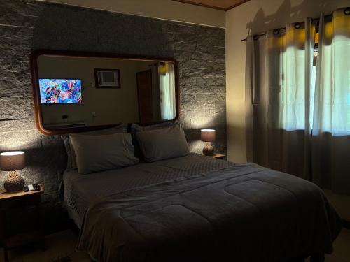 1 dormitorio con 1 cama con espejo y TV en Estação Serramar, en Lumiar