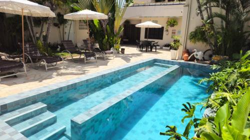 a blue swimming pool with stairs and umbrellas at Graciosa Suites in Praia do Frances