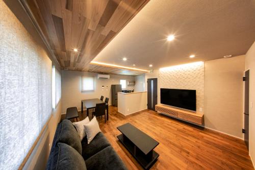 a living room with a couch and a tv at Sky deck for rent! Fuji view Open-air bath New building in Fujiyoshida