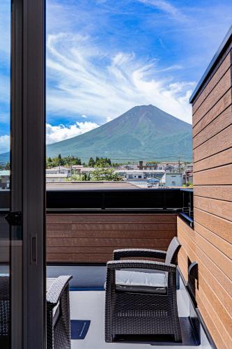 a balcony with a table and chairs and a mountain at Sky deck for rent! Fuji view Open-air bath New building in Fujiyoshida