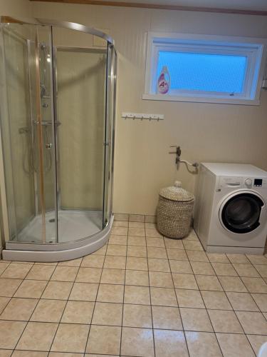 y baño con ducha y lavadora. en Sigridtunet - 4 bedroom Arctic experiences by the sea, with great opportunities to see the Northern lights dancing just for you!, en Tromsø