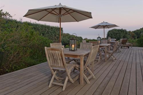 a wooden table and chairs with an umbrella on a deck at Mosselberg on Grotto Beach in Hermanus