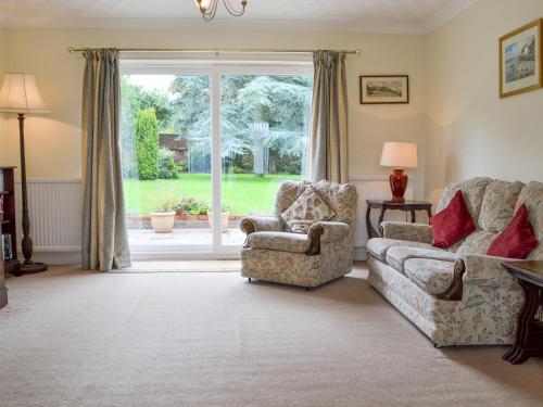 Una sala de estar con un sofá y una silla y una ventana. en Sea Glimpse, en West Runton