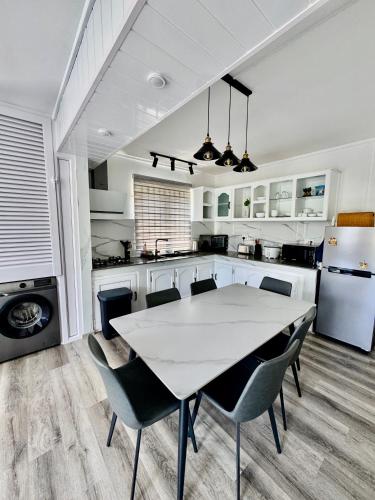 a white kitchen with a white table and chairs at Le Repos Blue Apartment in Pereybere