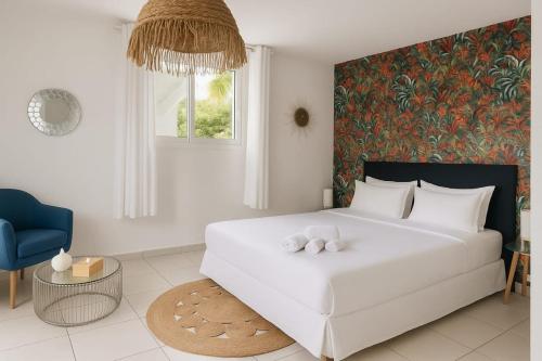 a bedroom with a large white bed and a blue chair at Villa Lawrencia, meublé de tourisme 4 étoiles in Morne-à-lʼEau