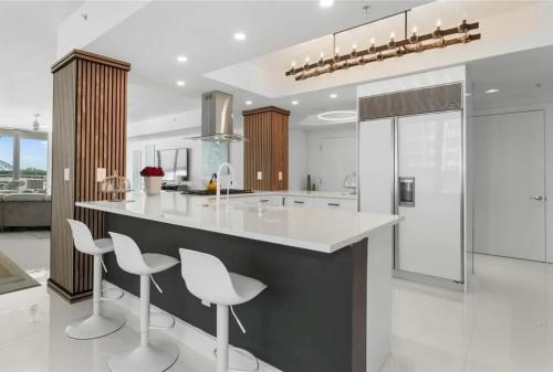 a kitchen with white counters and white stools at Southeast Oceanfront Residence in Hollywood Beach