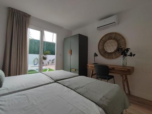 a bedroom with a bed and a desk and a window at Bungalow con jardín privado junto al Yumbo in Playa del Ingles