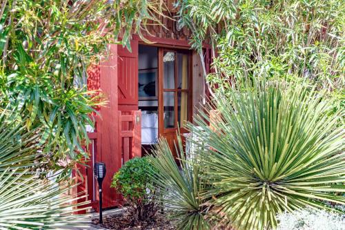a red front door of a house with palm trees at Hotel de La Plage in Contis-les-Bains