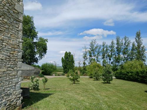 een tuin met bomen en een stenen gebouw bij Chez Mémé, gite proche Futuroscope in Saint-Clair
