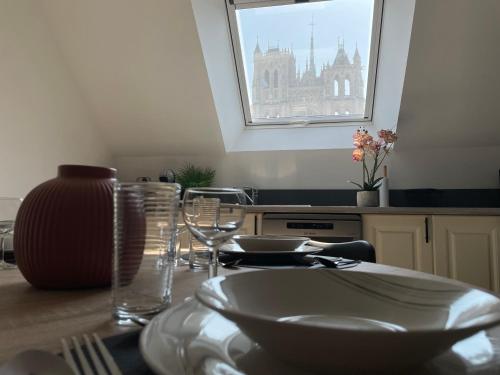 a table with plates and glasses and a window at Vue Cathedrale, Elegance & Lumière à Amiens in Amiens