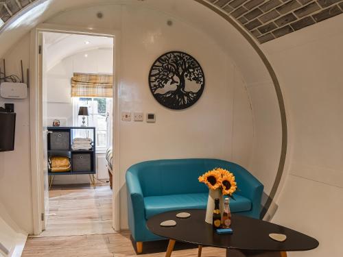 a living room with a blue couch and a table at The Orb in Hastingleigh