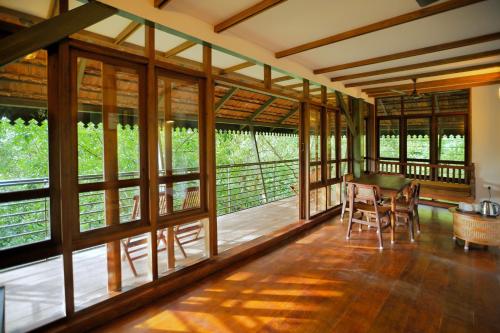 une pièce avec des fenêtres, une table et des chaises dans l'établissement Solitude Munnar - Tree house, à Munnar