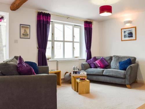 a living room with two couches and a window at Primrose Cottage in Little Rissington