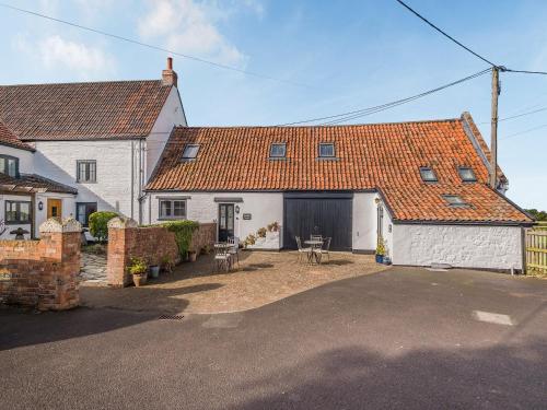 a large white house with a yard with chairs at Horseshoe Cottage-Uk37360 in Lympsham