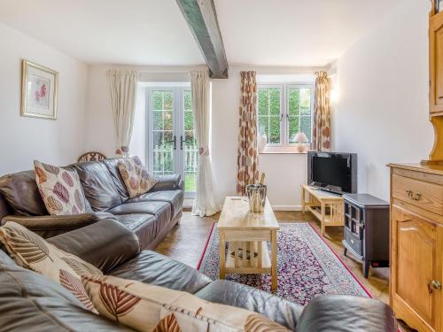 a living room with a couch and a tv at Horseshoe Cottage-Uk37360 in Lympsham