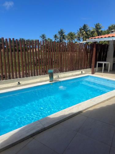 una piscina frente a una valla de madera en Beach house, en Conde