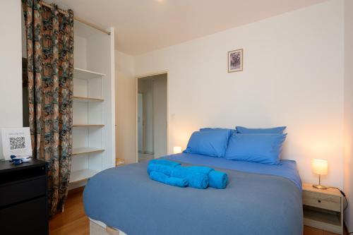a bedroom with a blue bed with blue pillows at La loge du Minotaure, parking et bureaux in Toulouse