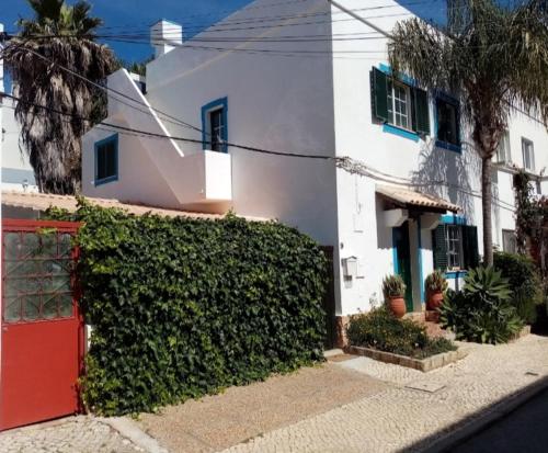 a white house with a red door and a hedge at Casa Rustica - Courtyard House in Olhão