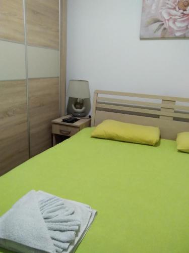 a bedroom with a green bed with a yellow blanket at Apartmani Krsic 5477399 in Palisat