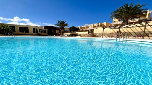a large blue swimming pool with palm trees and buildings at Welooveyou Blue Collection in Costa Calma